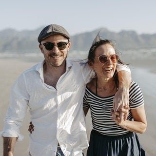 Ein glückliches Paar am Strand. Symbolbild für gelingende Liebe und Beziehungen. Für eine stabile Bindung ist Sex sehr wichtig, sagt Paarberater Christian Thiel.